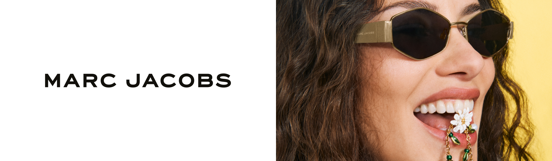 Eine Frau mit Sonnenbrille lächelt mit einer Blume im Mund, mit „Marc Jacobs“ Schriftzug.