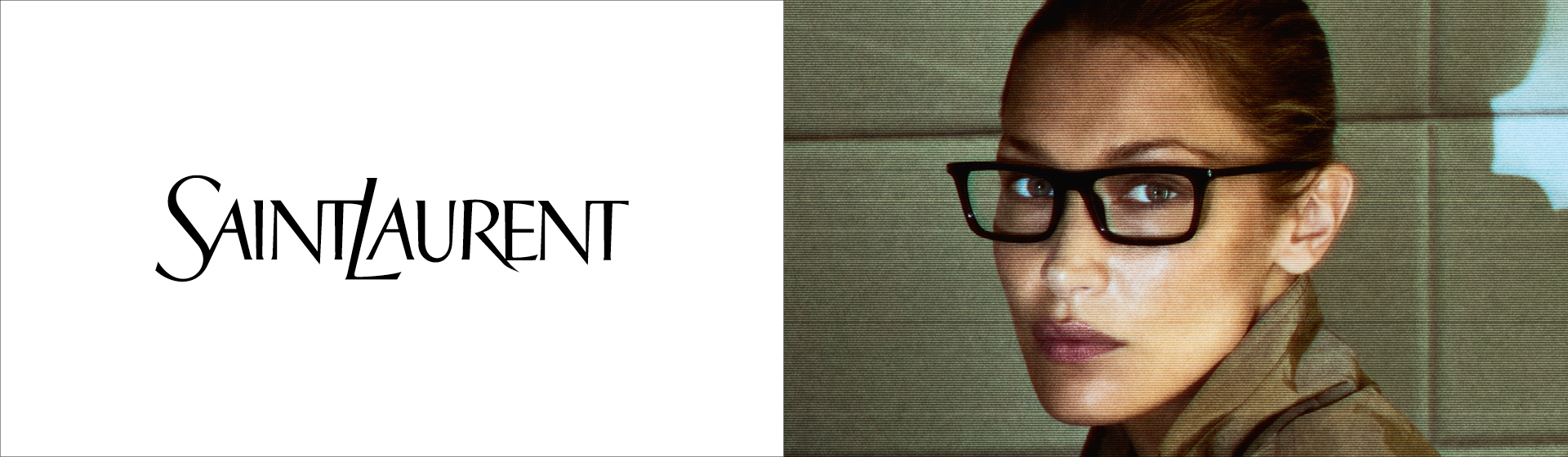 Osoba w dużych okularach i trenczu, siedząca przed wyłożoną kafelkami ścianą z napisem „Saint Laurent” nad nią.