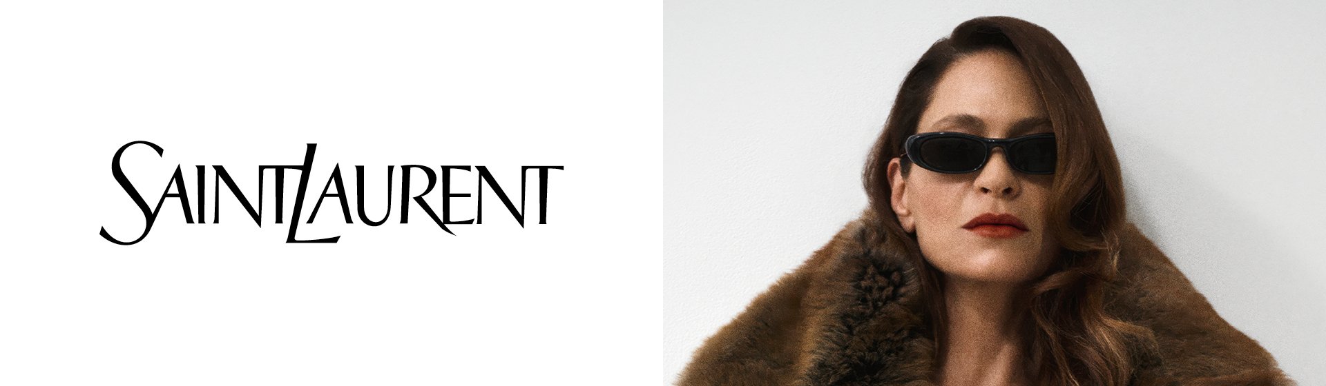 Widać logo Saint Laurent. Kobieta o długich włosach, w okularach przeciwsłonecznych i płaszczu z futrzanym kołnierzem, pozująca na białym tle.