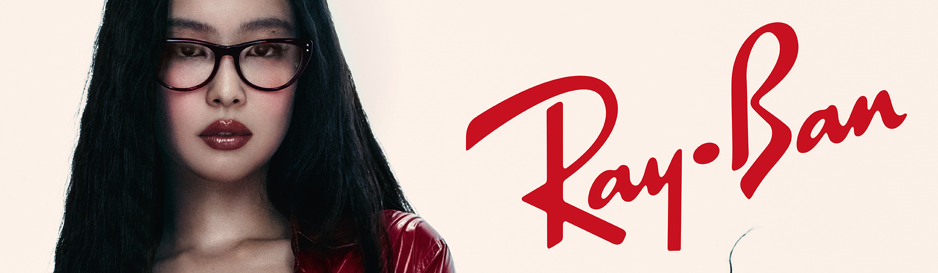 Una donna dai lunghi capelli neri indossa una giacca rossa e degli occhiali. Sopra è visibile il logo Ray-Ban.