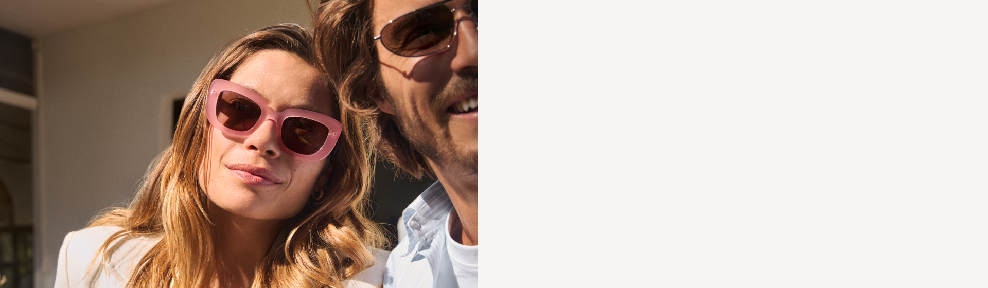 Primo piano di una donna sorridente con lunghi capelli biondi che indossa occhiali da sole rosa oversize.