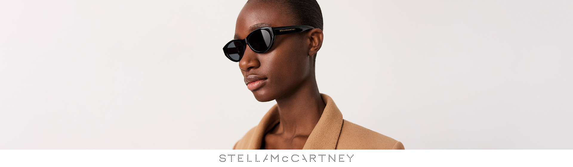 Frau mit Sonnenbrille von Stella McCartney vor hellem Hintergrund.
