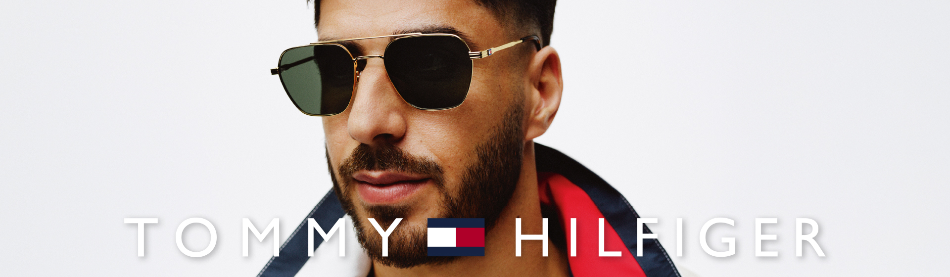 Mężczyzna nosi złote okulary przeciwsłoneczne marki Tommy Hilfiger.