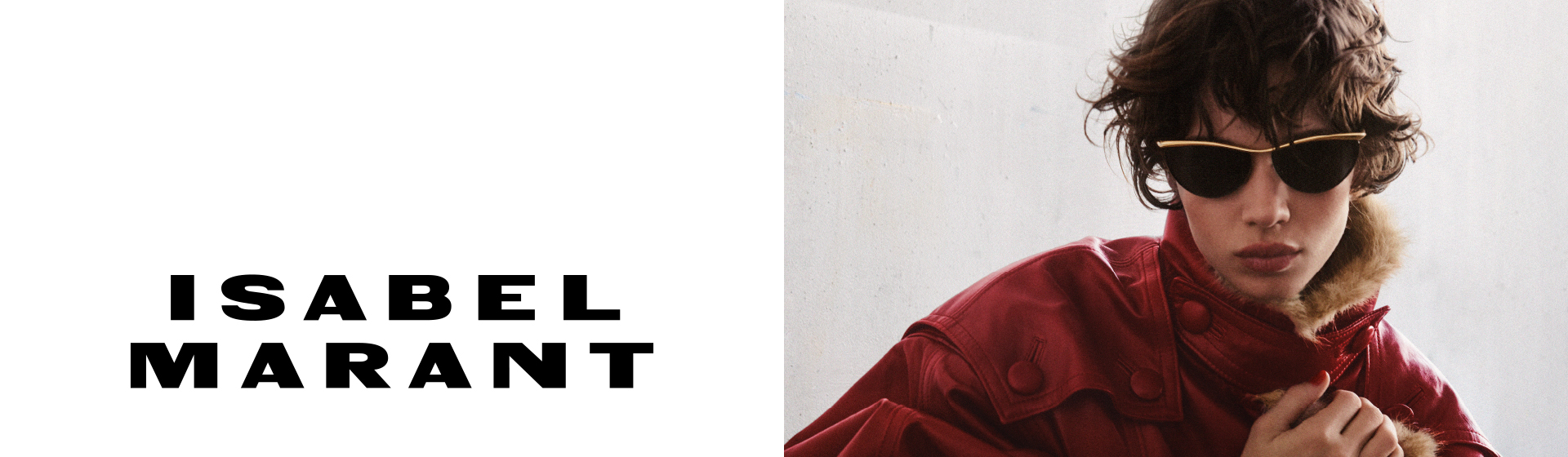 Eine Person mit zerzaustem Haar, die eine Cat-Eye-Sonnenbrille und eine rote Jacke mit Pelzkragen trägt, vor einem einfarbigen Hintergrund. Der Text lautet „Isabel Marant“.