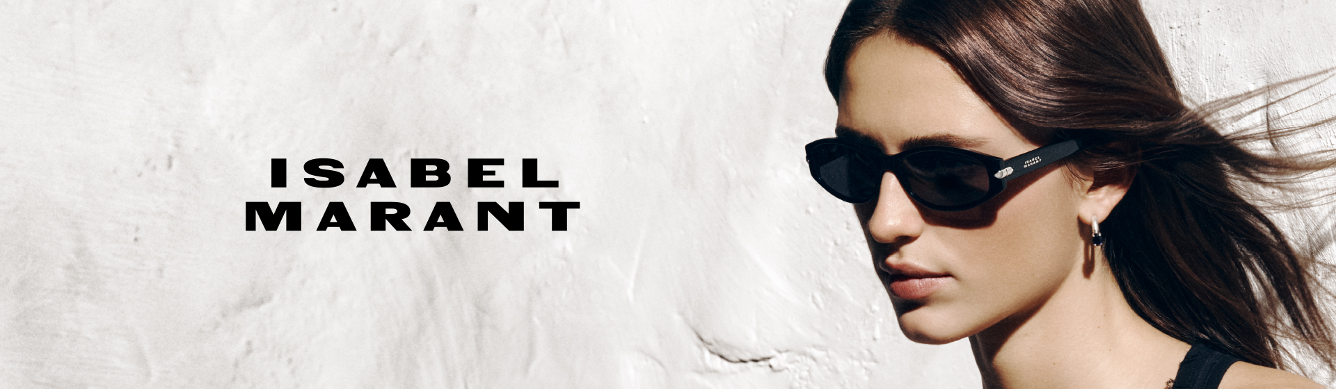 Kobieta w okularach przeciwsłonecznych i kolczykach, z długimi, falującymi włosami, obok napisu „ISABEL MARANT”.