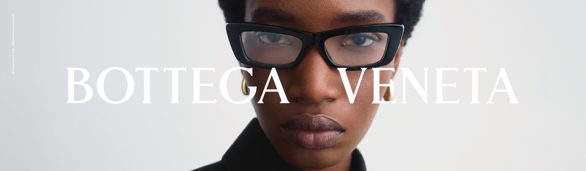 Persona con capelli corti, occhiali rettangolari e camicia nera con colletto, con la scritta “Bottega Veneta” sopra l'immagine.
