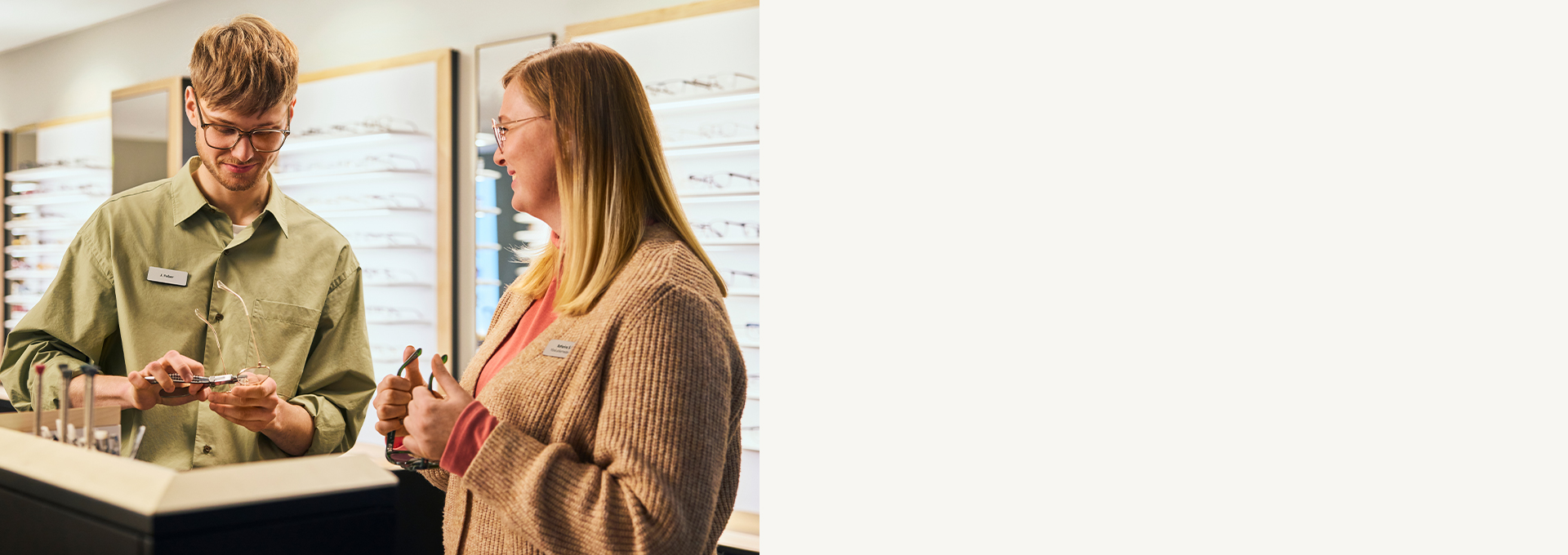 Ein Verkäufer zeigt einem Kunden in einem Brillengeschäft Brillen, im Hintergrund sind Ausstellungsregale zu sehen.