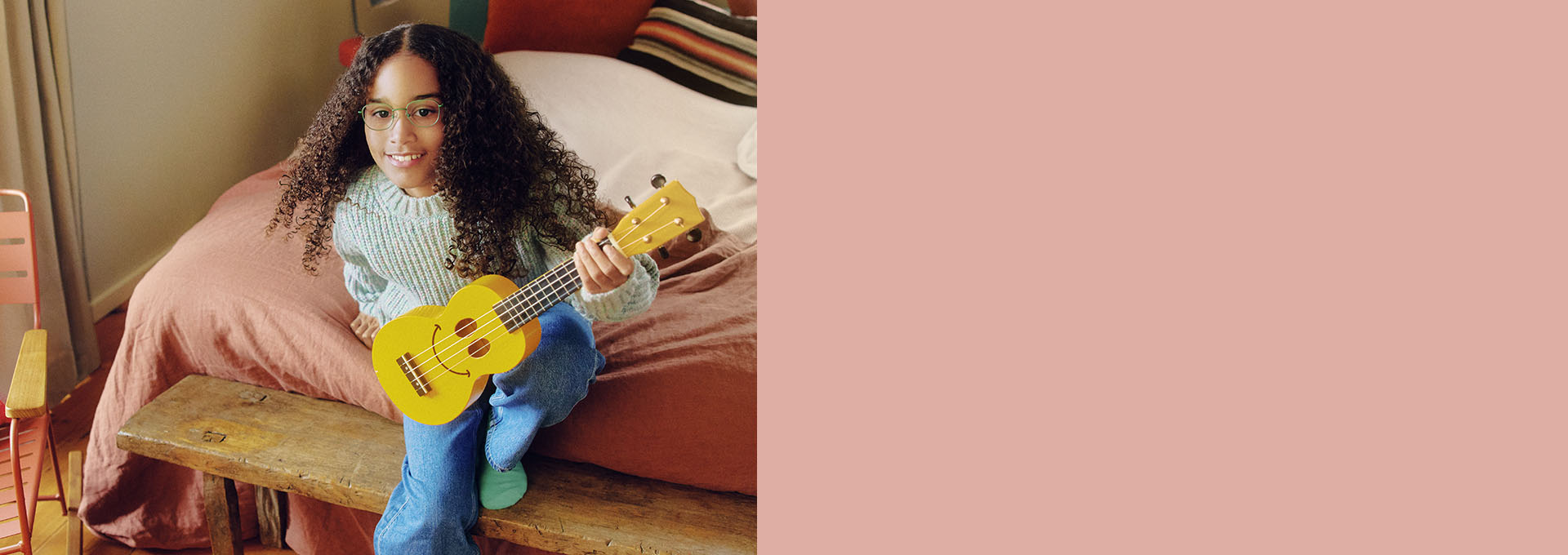 Ragazza con gli occhiali che suona una piccola chitarra gialla.