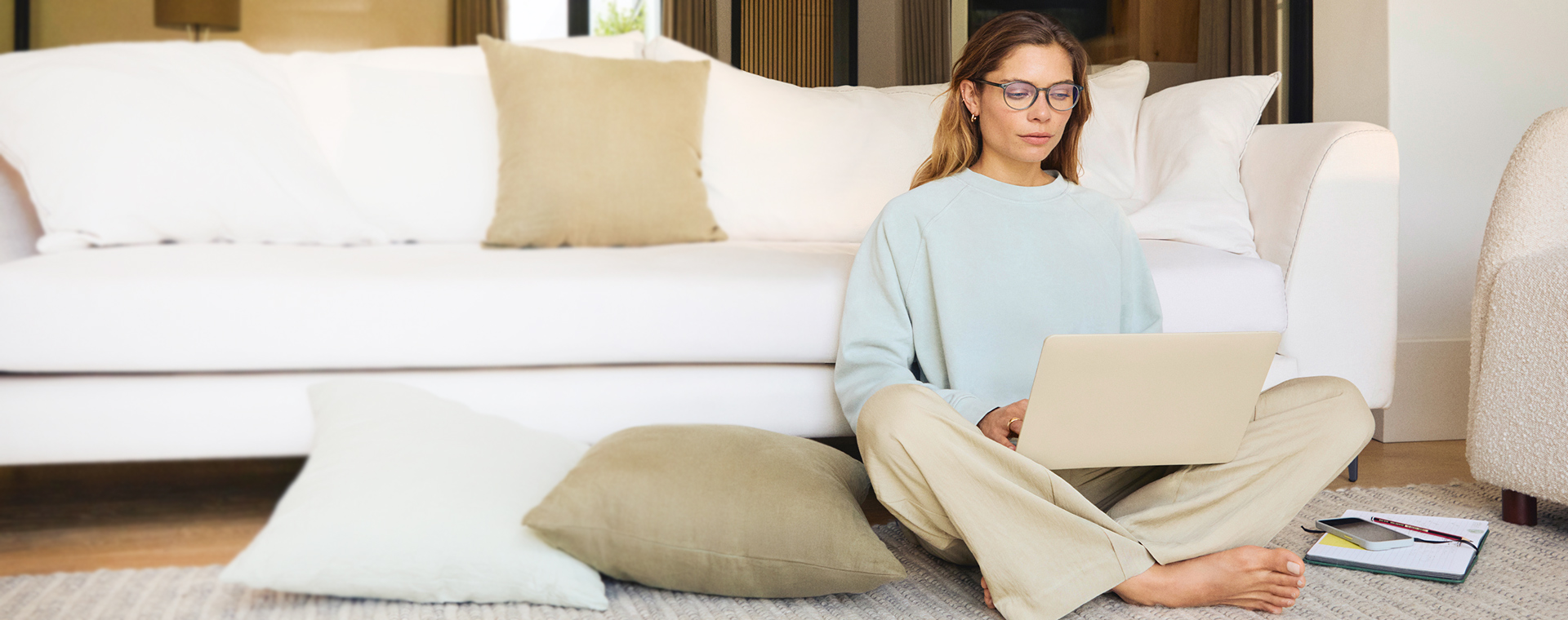 Frau sitzt auf dem Boden mit einem Laptop.