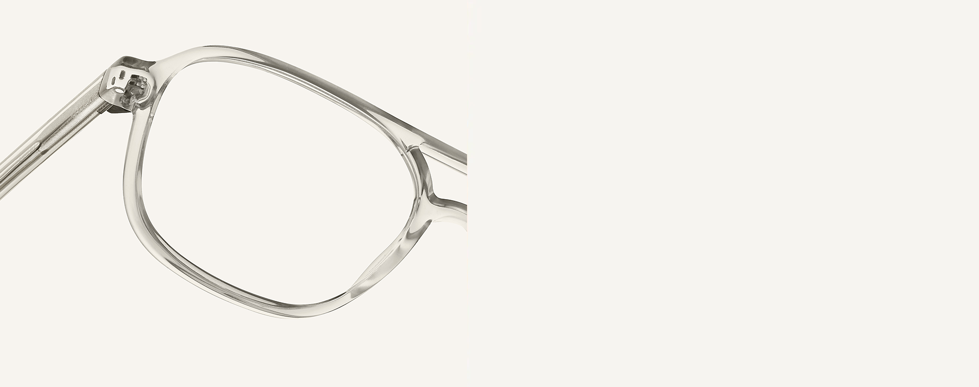 Zbliżenie cienkich, przezroczystych oprawek okularów na neutralnym tle, pokazujące fragment soczewki i zausznika.