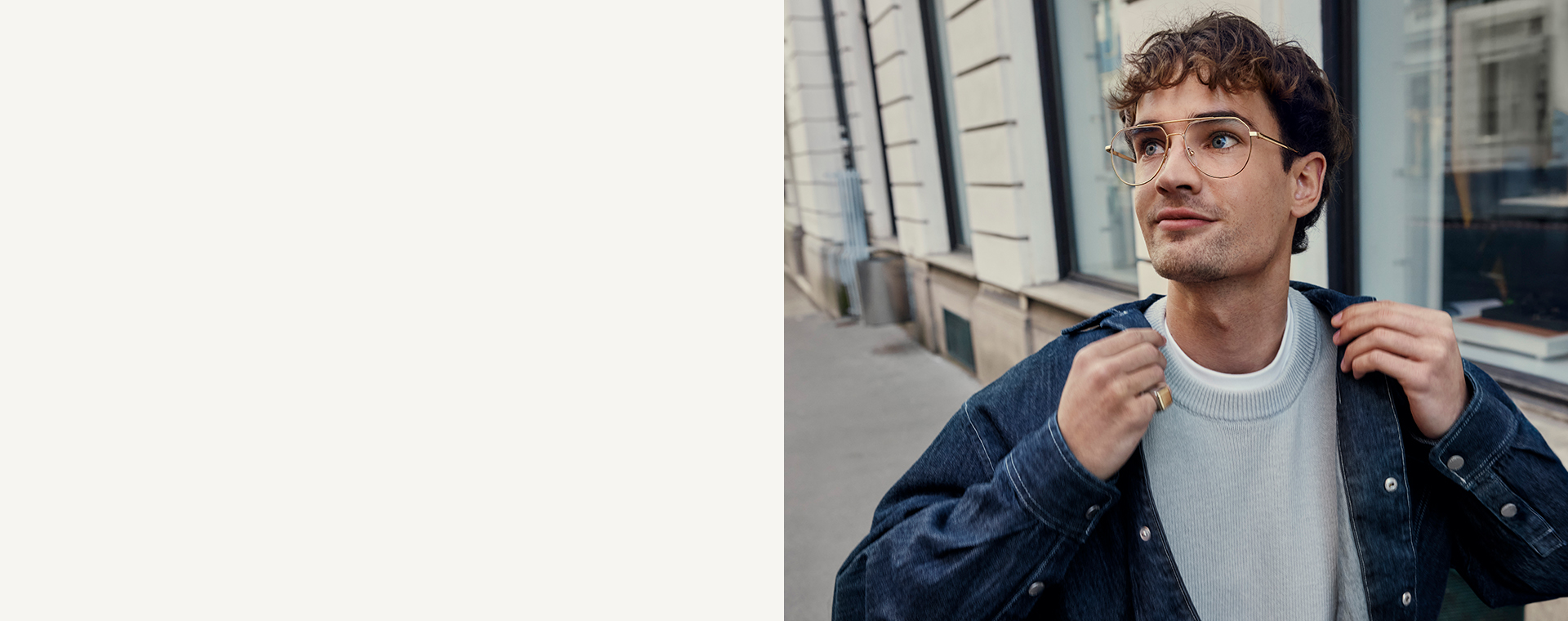 Junger Mann mit einer Brille in Aviator-Form steht vor einem Gebäude.