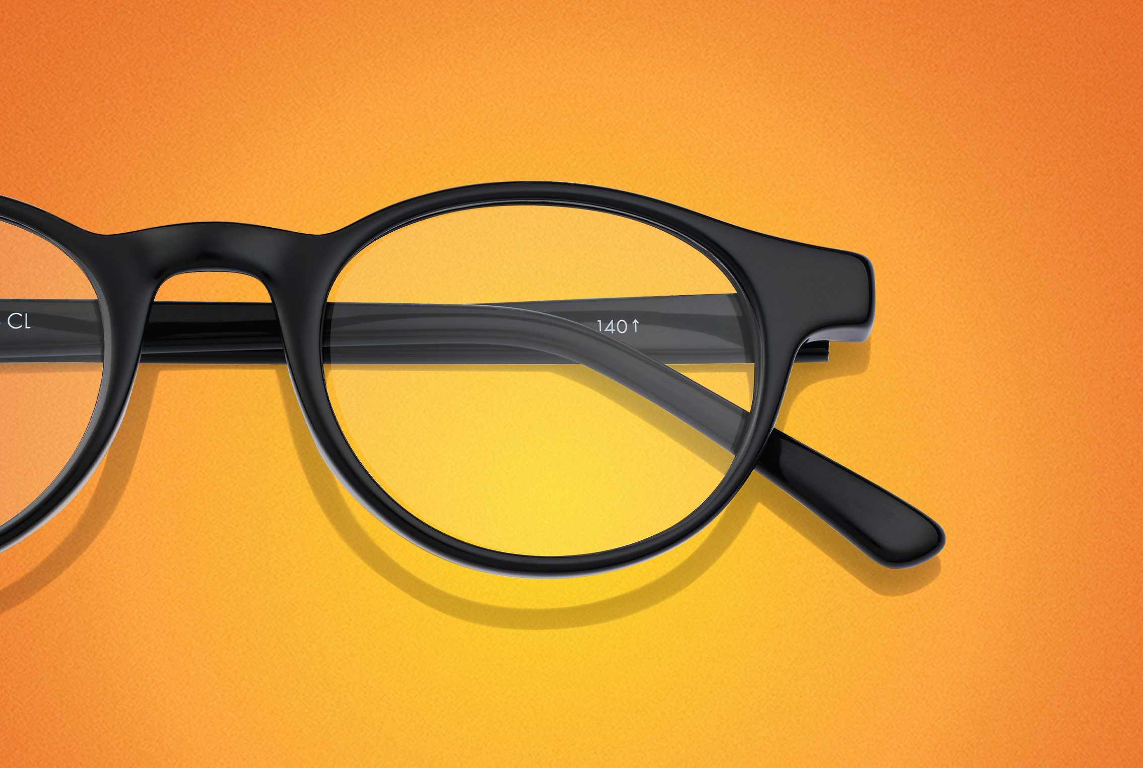 Runde schwarze Brille auf orangem Hintergrund.