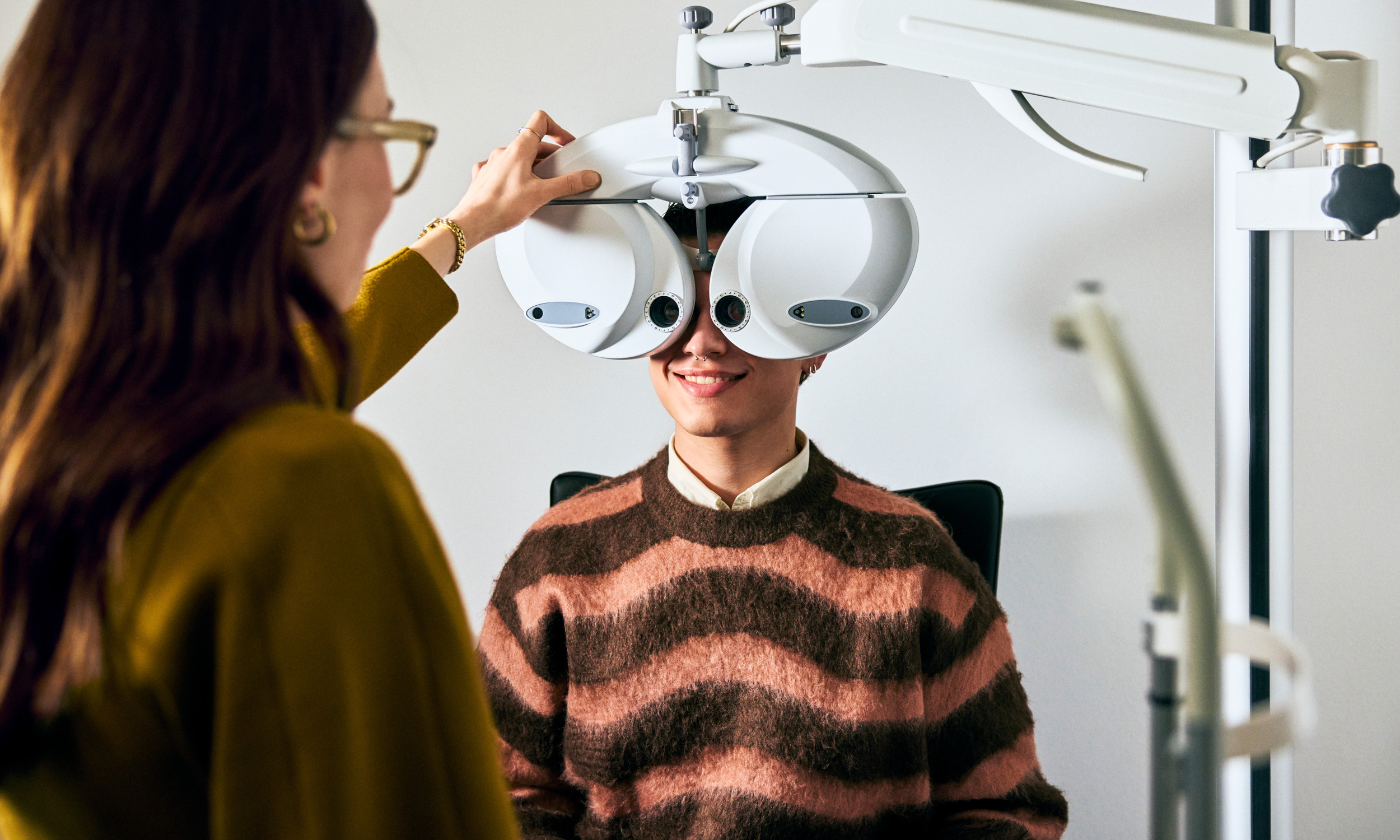 Person lächelt während eines Sehtests beim Optiker.