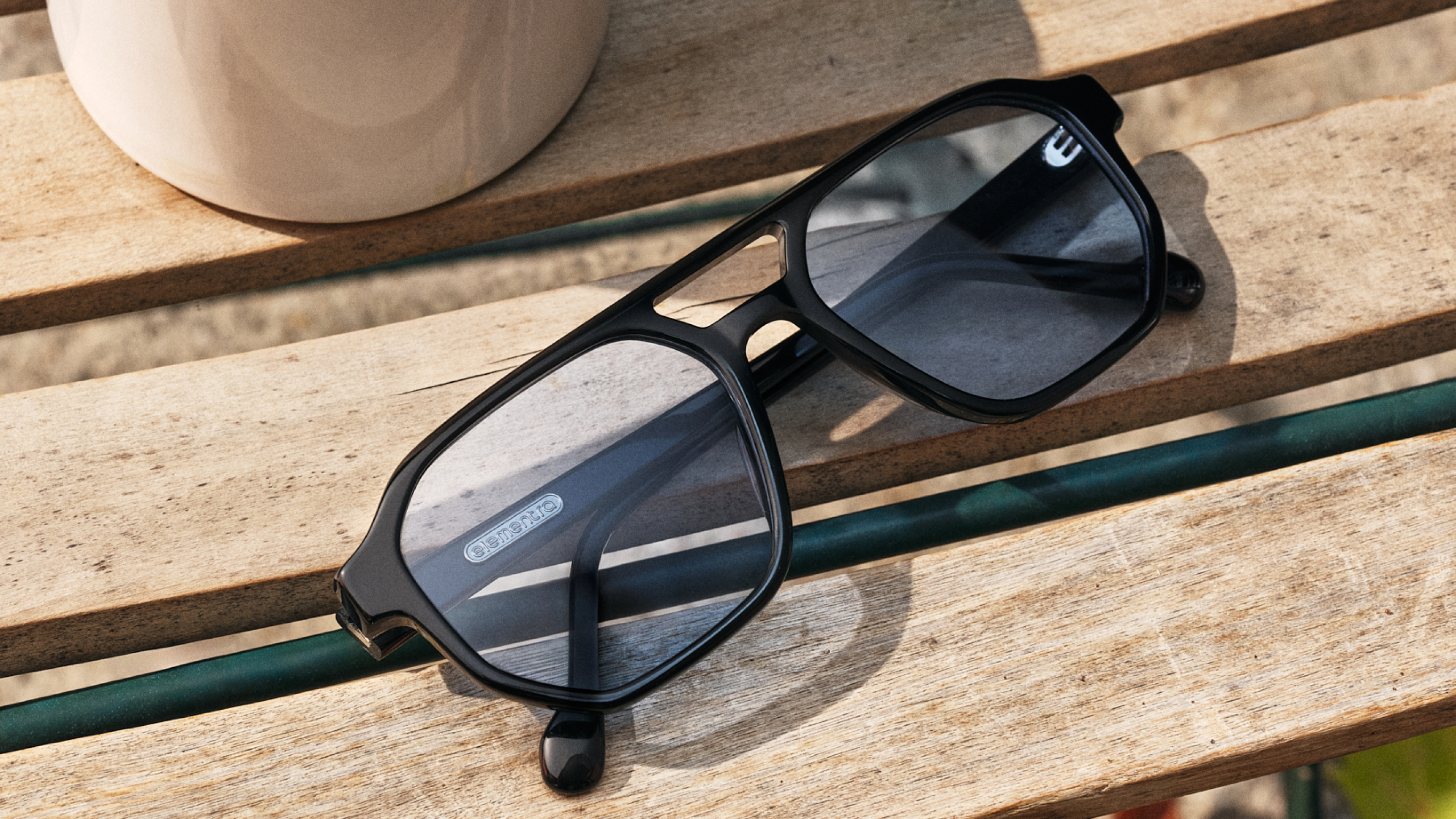 Eine Sonnenbrille liegt auf einer Holzbank.