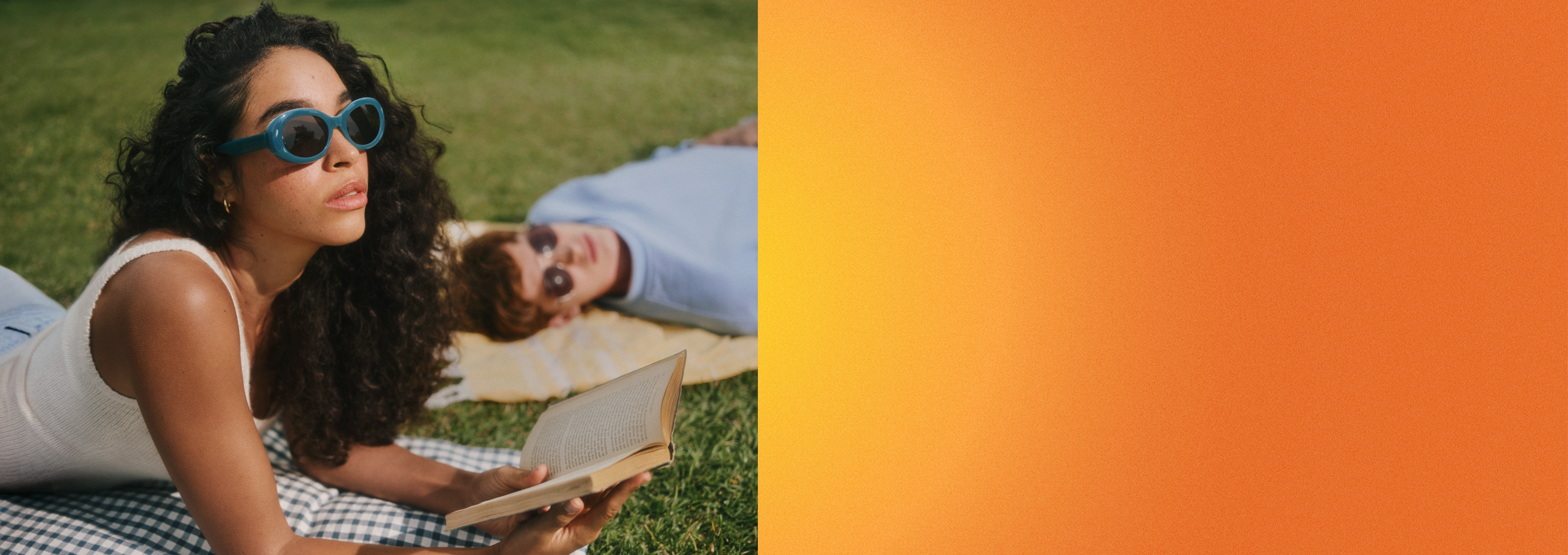 Frau mit Sonnenbrille liest auf dem Rasen, eine weitere ruht sich aus.