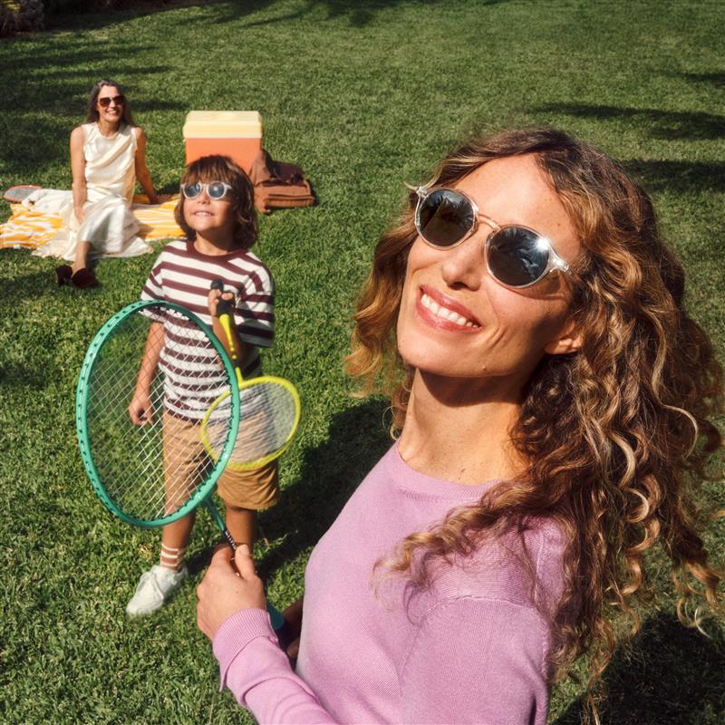 Eine Frau und zwei Kinder genießen Outdoor-Aktivitäten auf dem Rasen mit Schlägern.