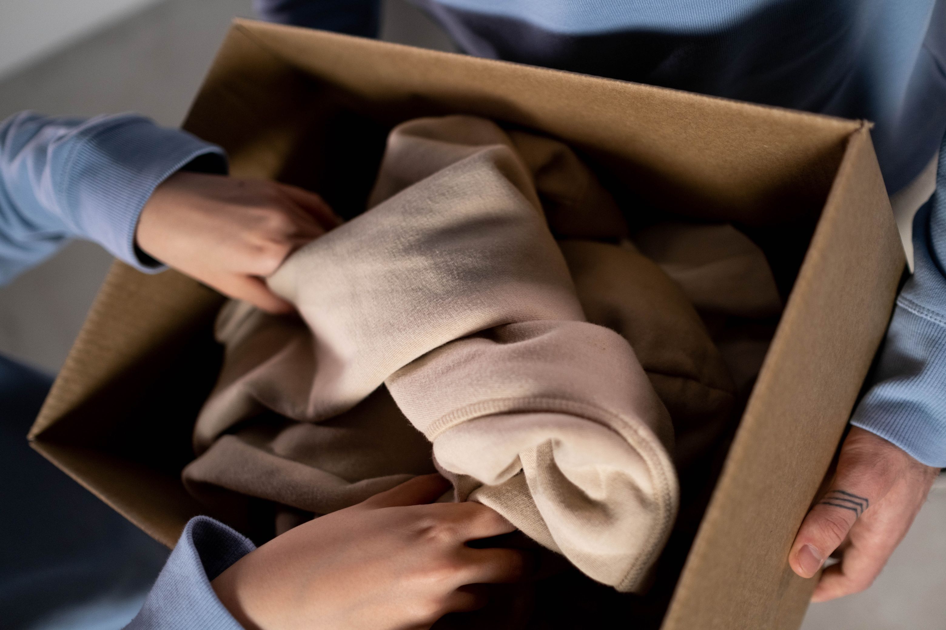 a person giving away a box of clothes to another person