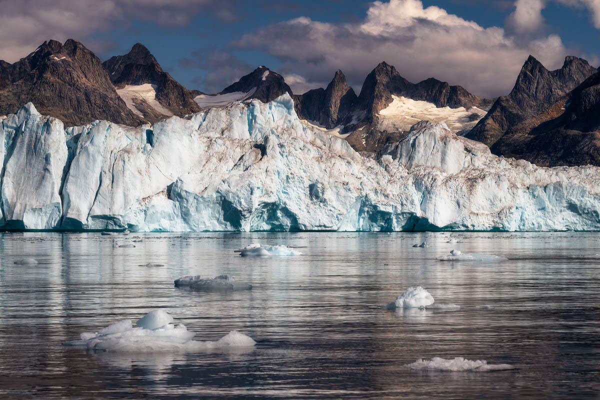 Berg Niialingaq hinter einem großen Eisberg im Sermilik-Fjord