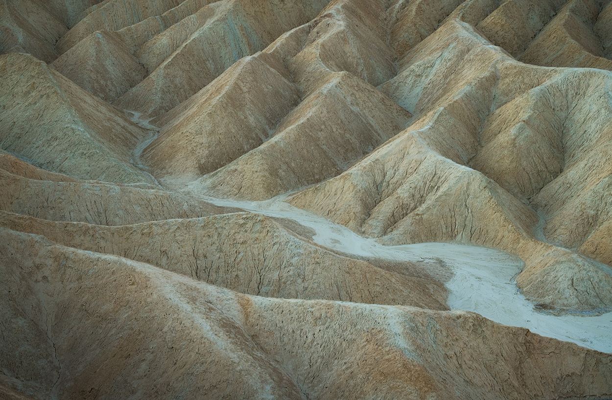 Rugged, eroded hills with a dry, dusty appearance, featuring ridges and valleys in muted earthy tones.