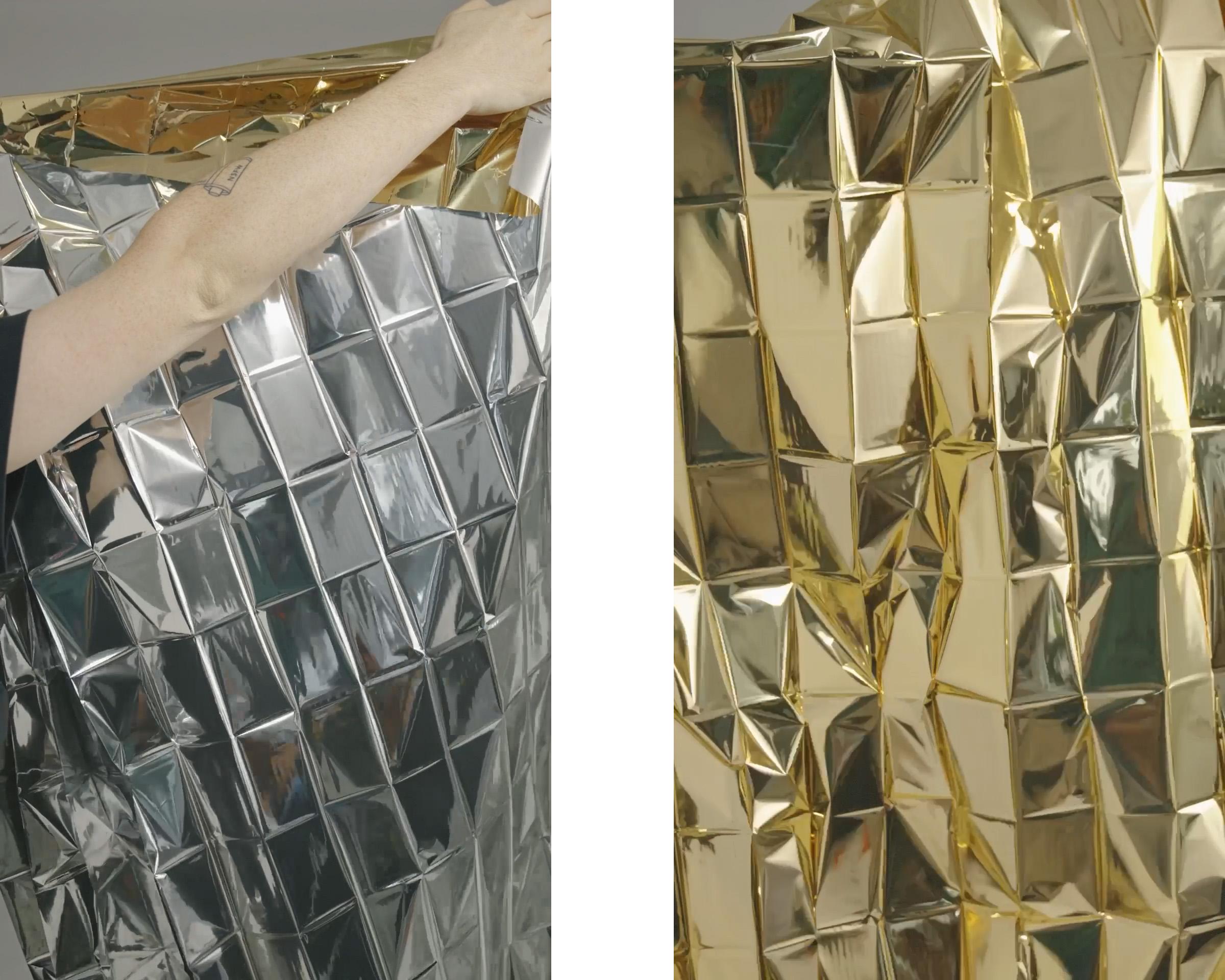 Person holding a reflective emergency blanket, silver on one side and gold on the other, displaying its crinkled texture.