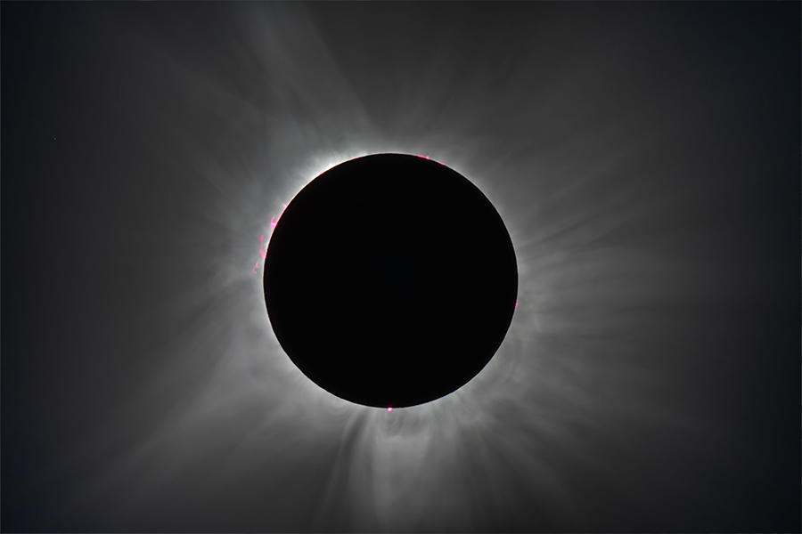 A total solar eclipse with a darkened sun and a bright corona surrounded by a soft radiating glow.
