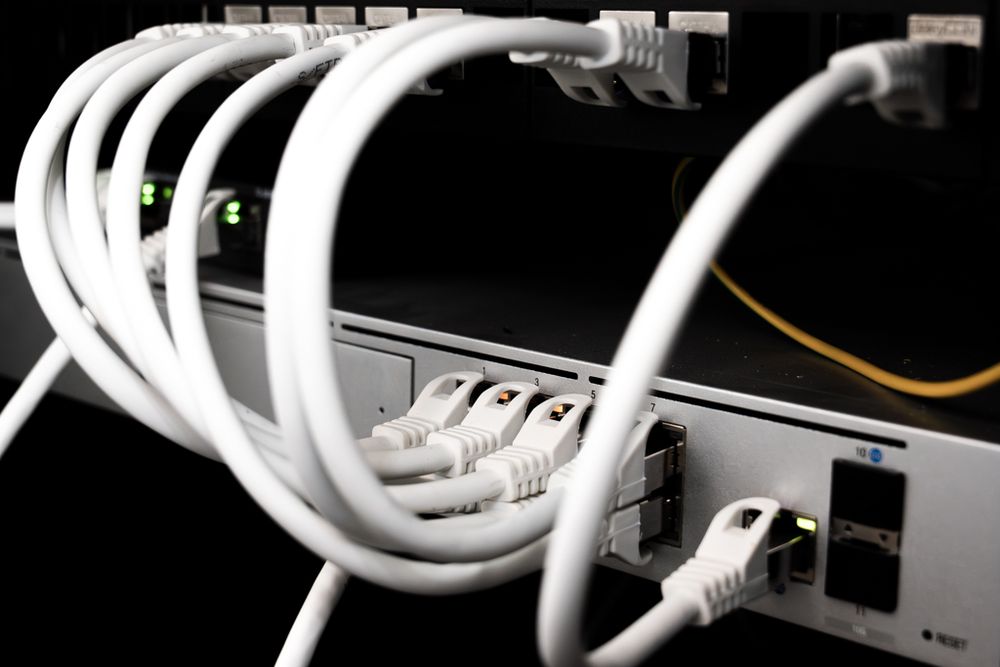 Netzwerkgeräte mit mehreren angeschlossenen weißen Ethernet-Kabeln
