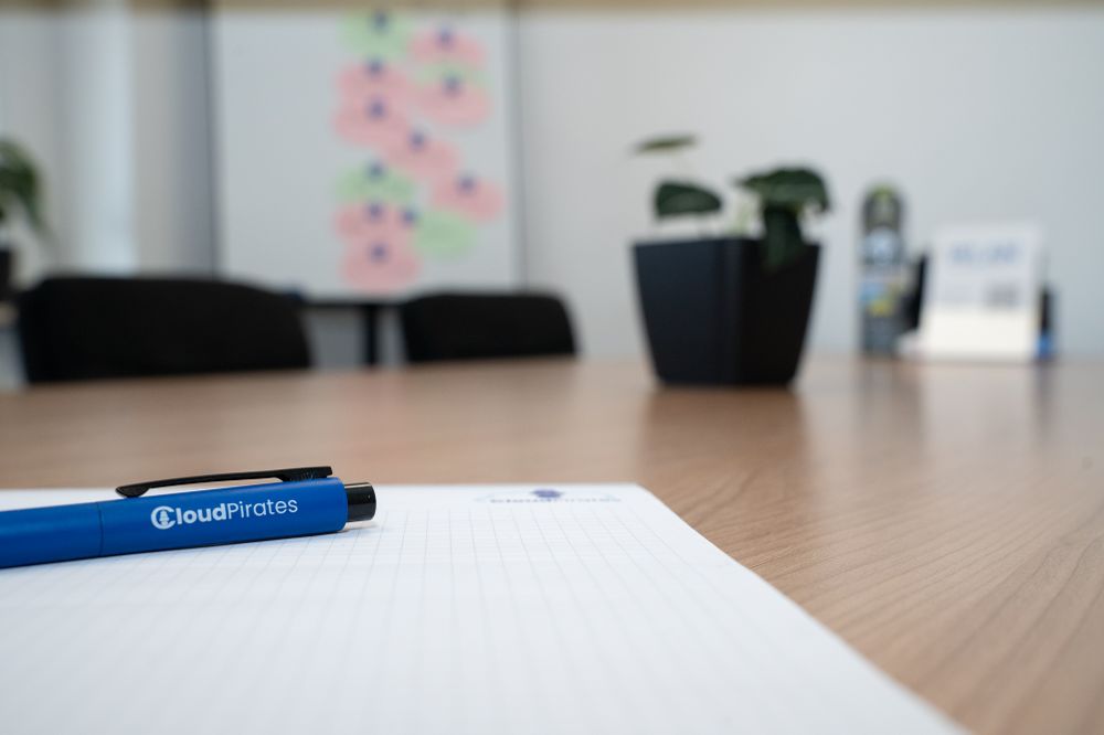 A blue pen with the "CloudPirates" logo on a paper block.