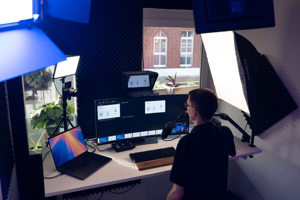 A wide view of our streaming room, showing many lights and monitors all around. Dennis is holding a presentation.