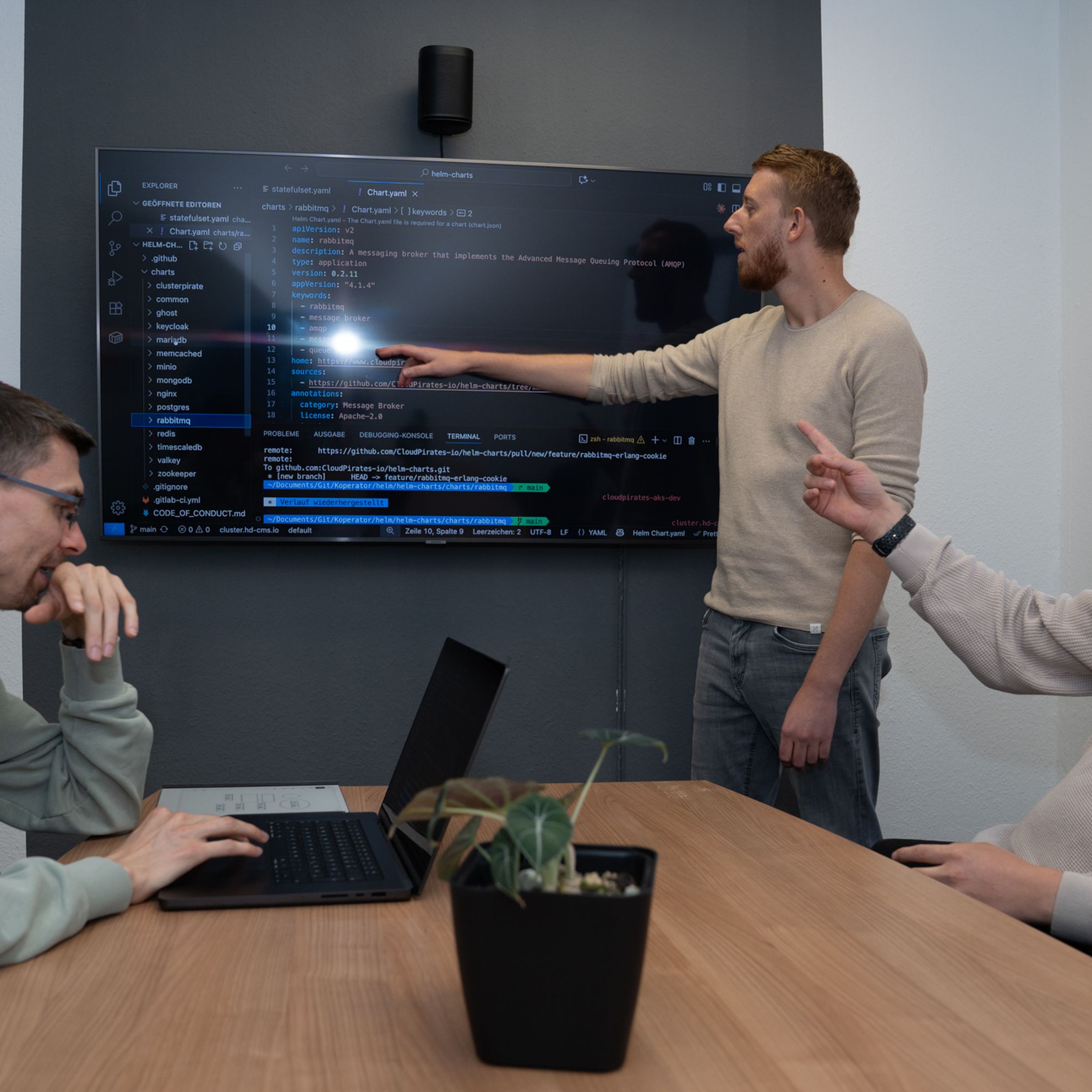 Dennis (left), Dominik (middle) and Yannick (right) are reviewing code displayed on a TV screen.