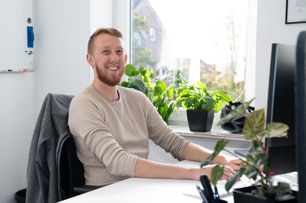 Dominik at his workplace, smiling towards the camera.
