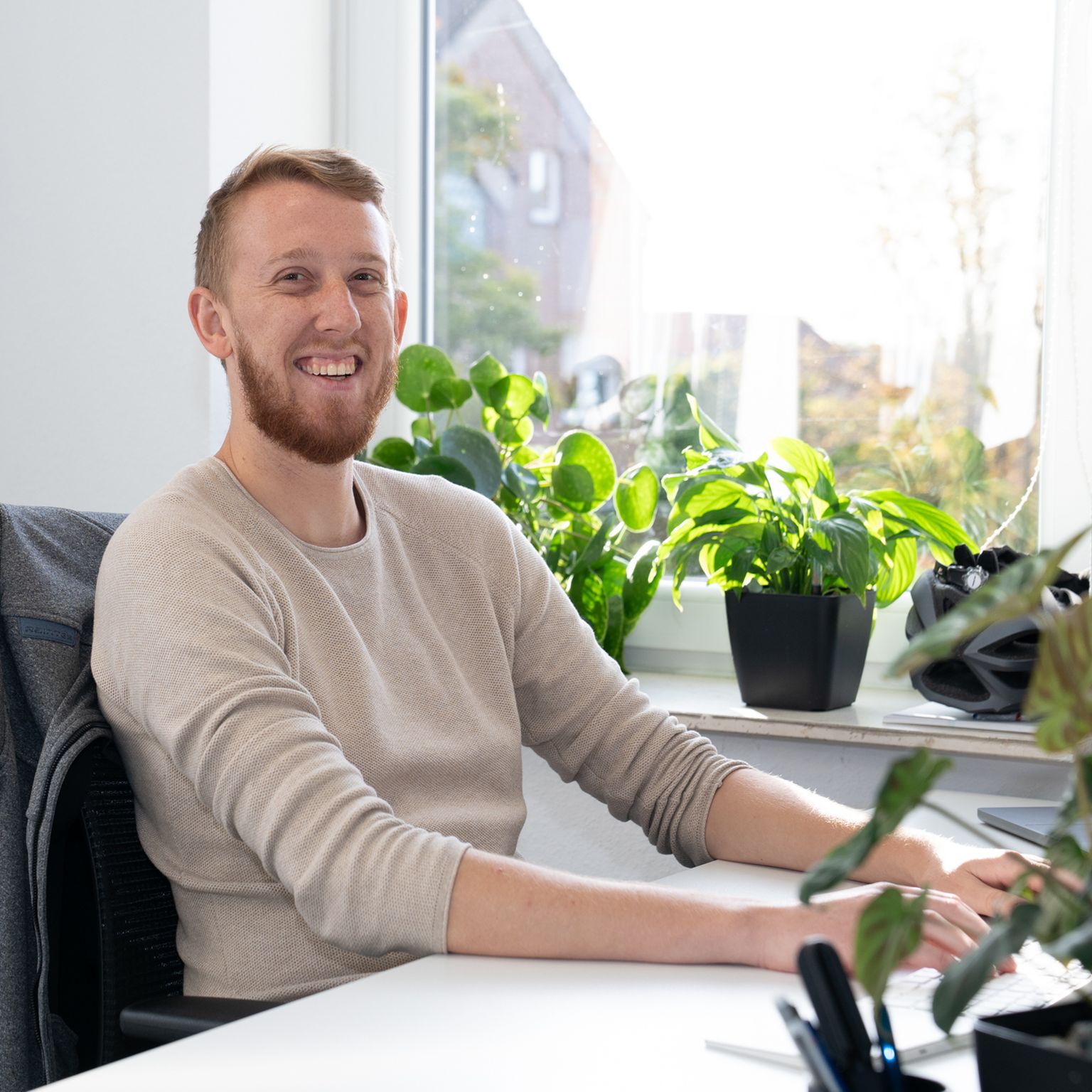 Dominik at his workplace, smiling towards the camera.