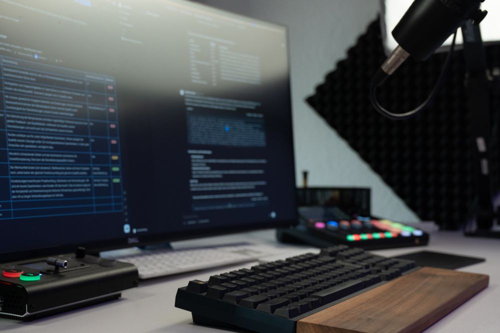 Our streaming setup (left to right): A wide-screen monitor, a camera switch, a keyboard, a sound board/mixer, a microphone, and a bunch of lights all around.