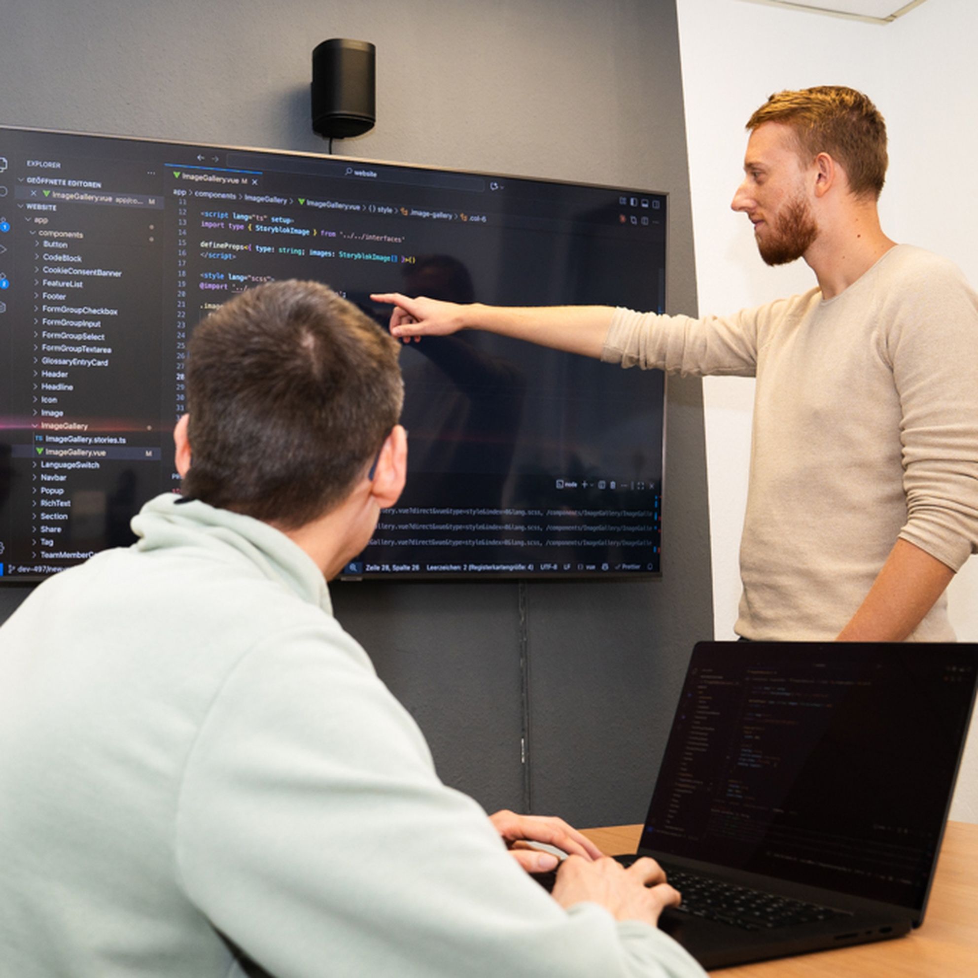 Zwei Entwickler besprechen gemeinsam Programmcode auf einem Bildschirm