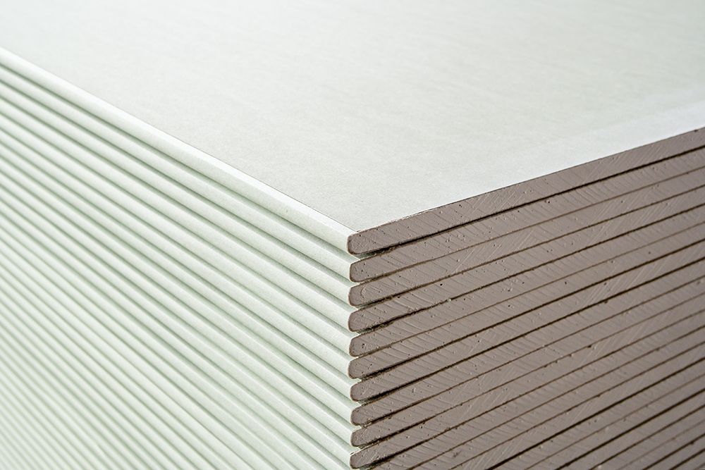 A stack of light green drywall sheets with neatly aligned edges viewed from the corner.