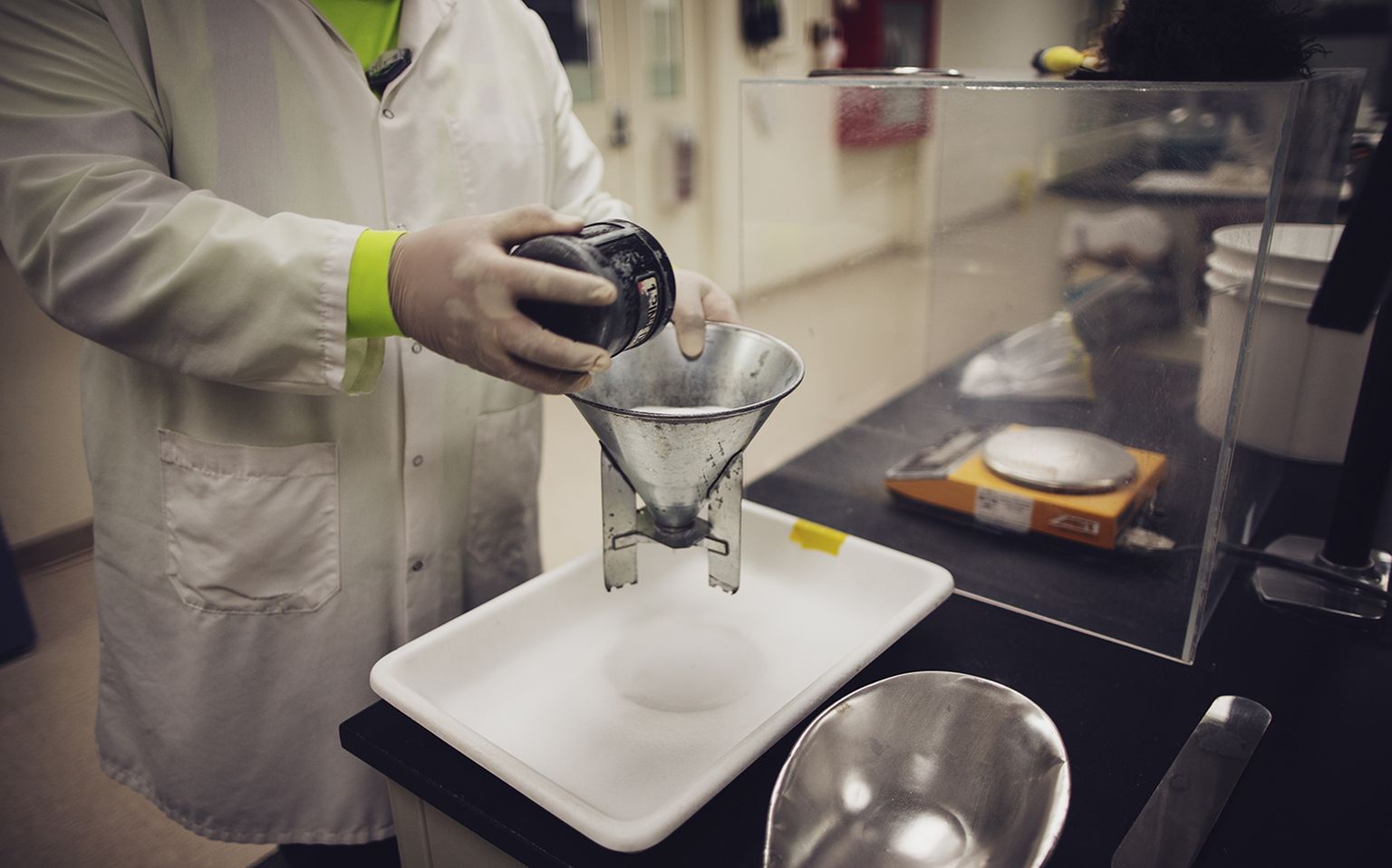 Man pouring borate powder through mesh sieves in a laboratory