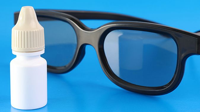 Pair of eyeglasses with an eye drop bottle