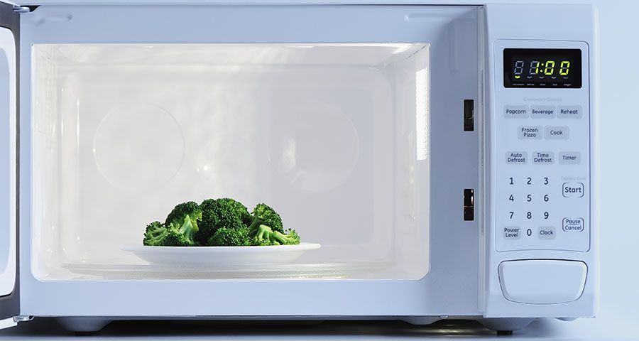 A plate of broccoli inside a microwave oven, with the timer set to one minute.