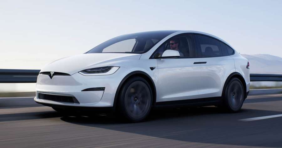 white tesla model x driving on a road