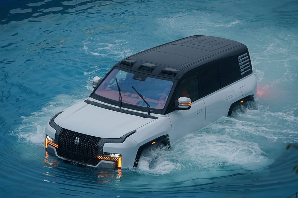 A white SUV navigates through shallow, swirling water, showcasing its capability to drive in wet conditions.