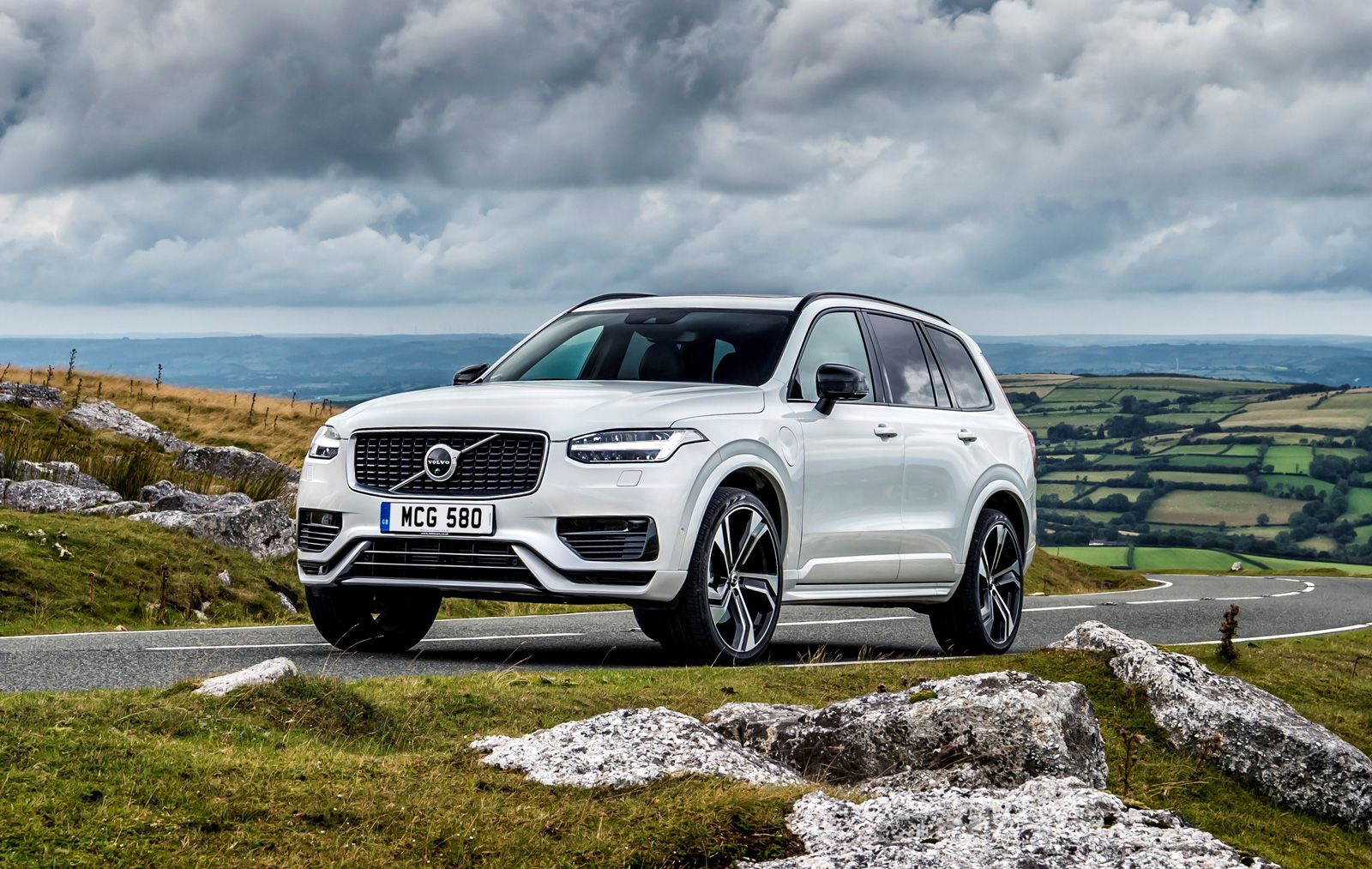 a white volvo xc90 driving round a country road