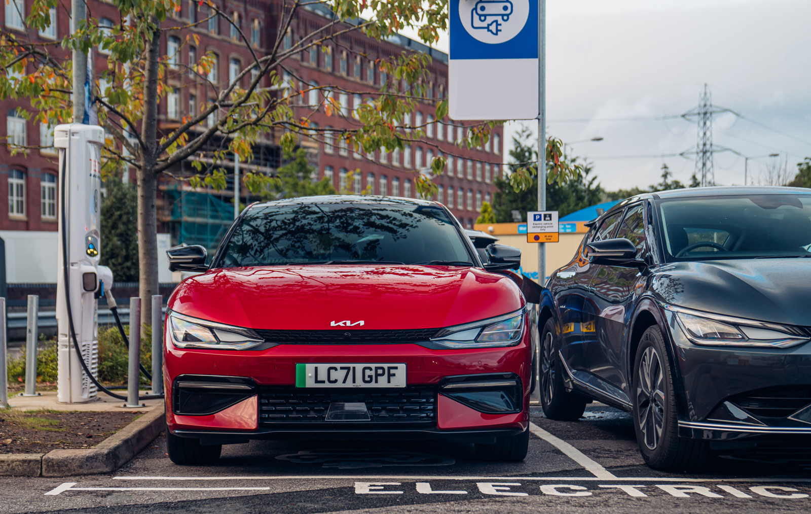 a red kia ev6 parked at a public EV charger in a carpark