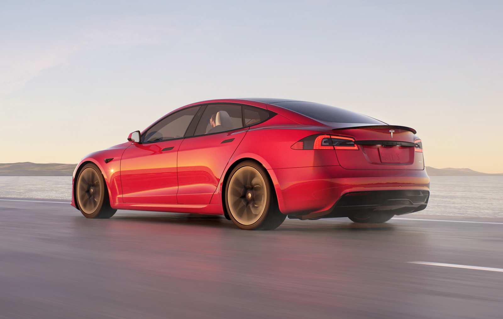 a red tesla model s driving on a road