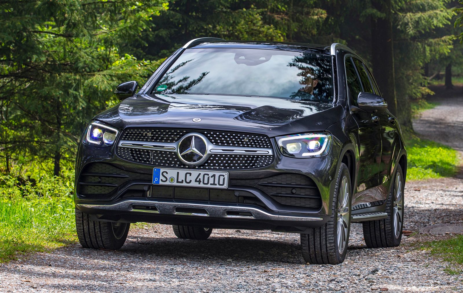 a black mercedes glc driving on an off-road trail among trees