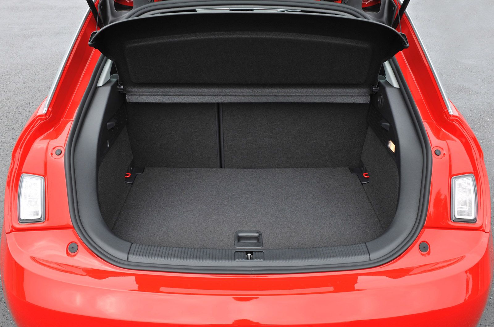Open trunk of a red car showing spacious, empty cargo area with dark interior lining.