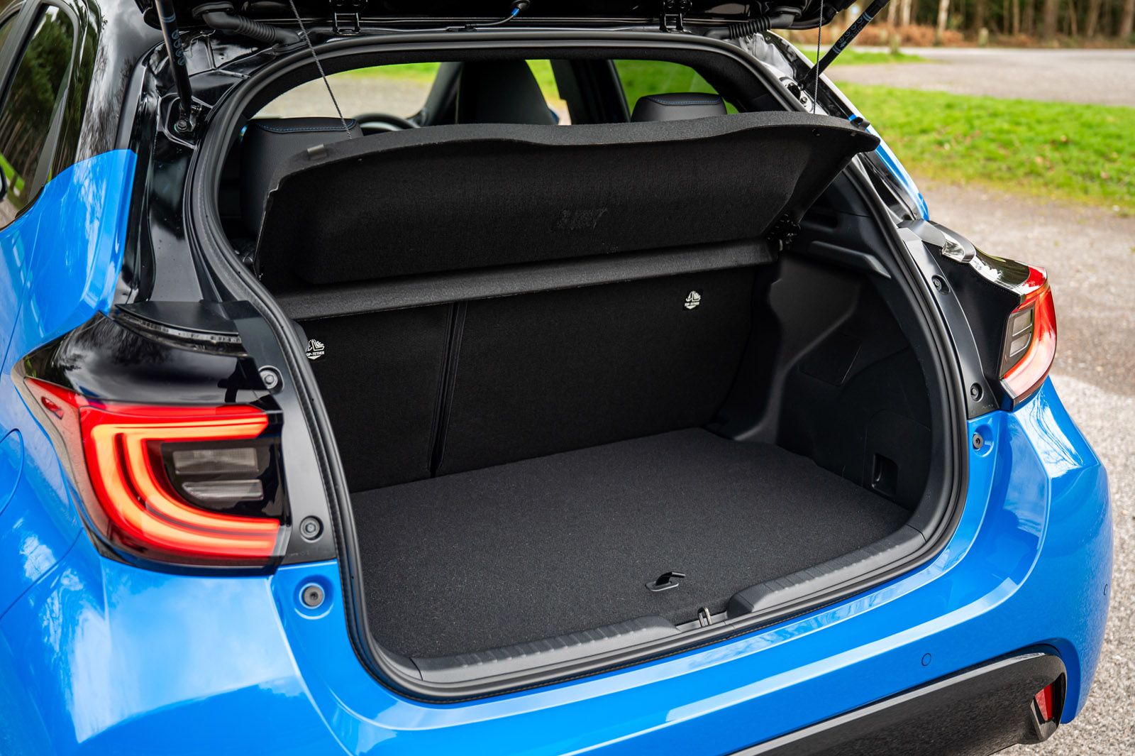 Open trunk of a blue car displaying a spacious cargo area with the rear seats in an upright position. Tail lights are visible.