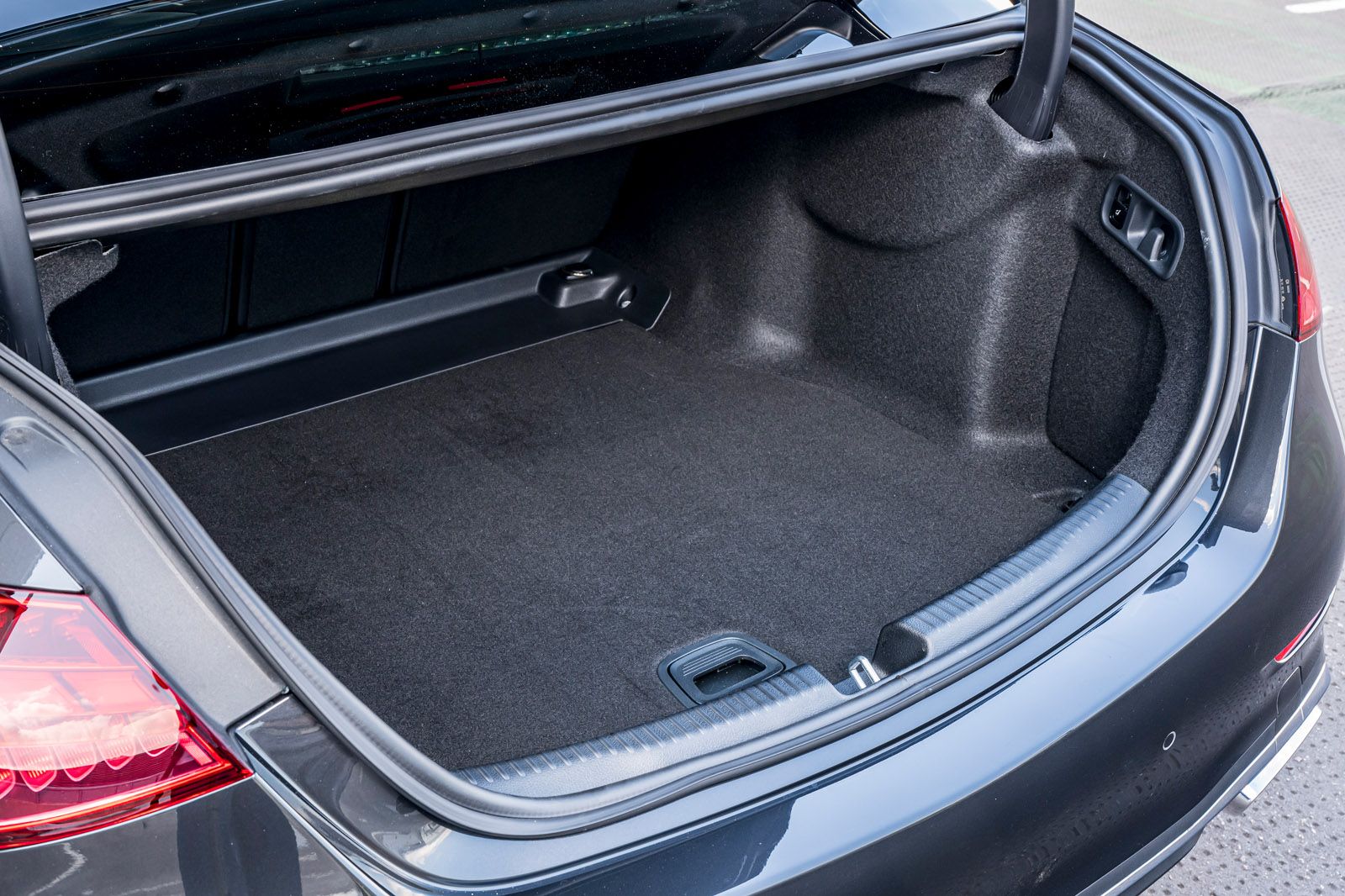 Open car trunk showing a spacious, clean interior with dark carpeting, positioned in a well-lit outdoor setting.