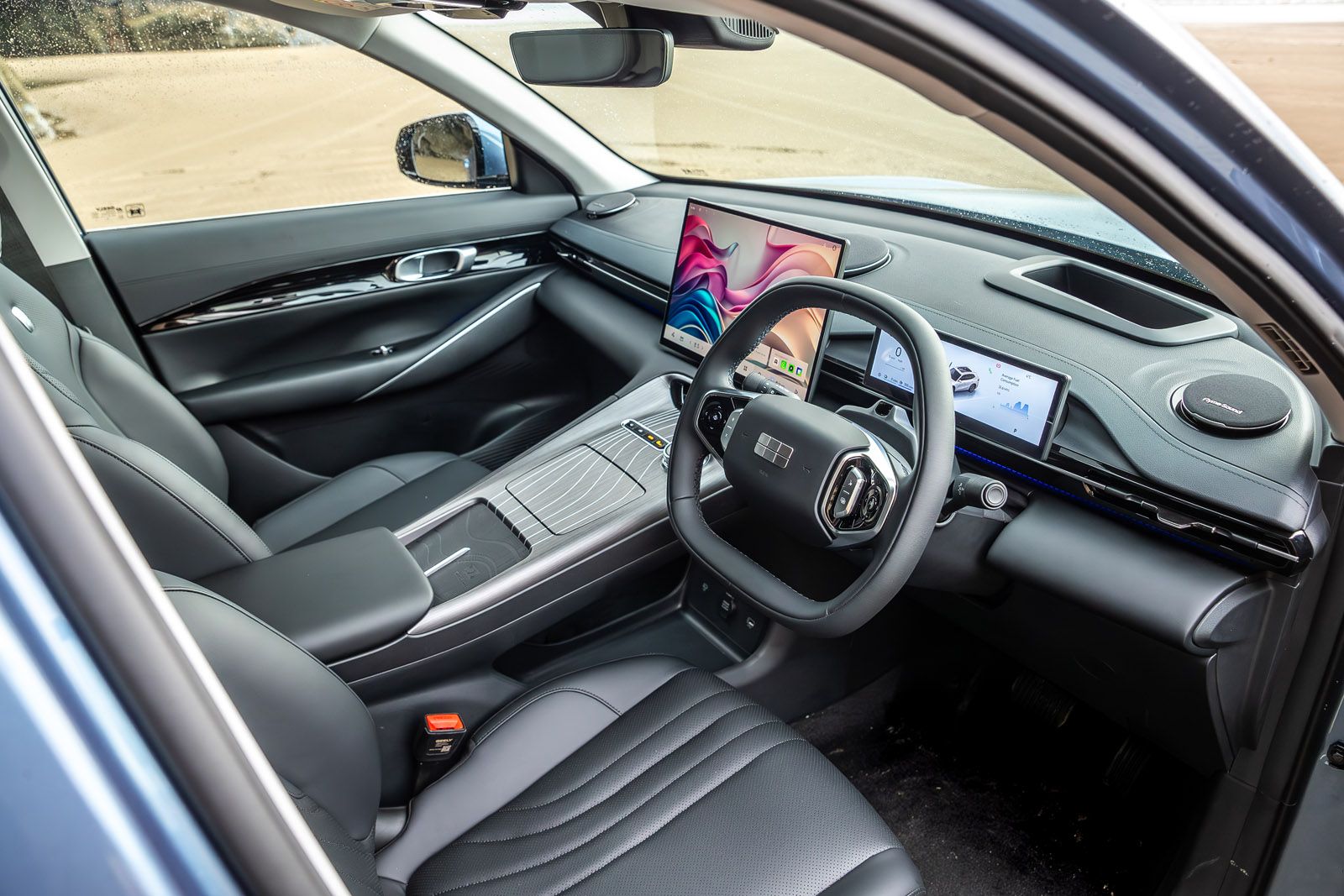 Modern car interior with a sleek dashboard, digital displays, and black leather seats, viewed from the driver's side.