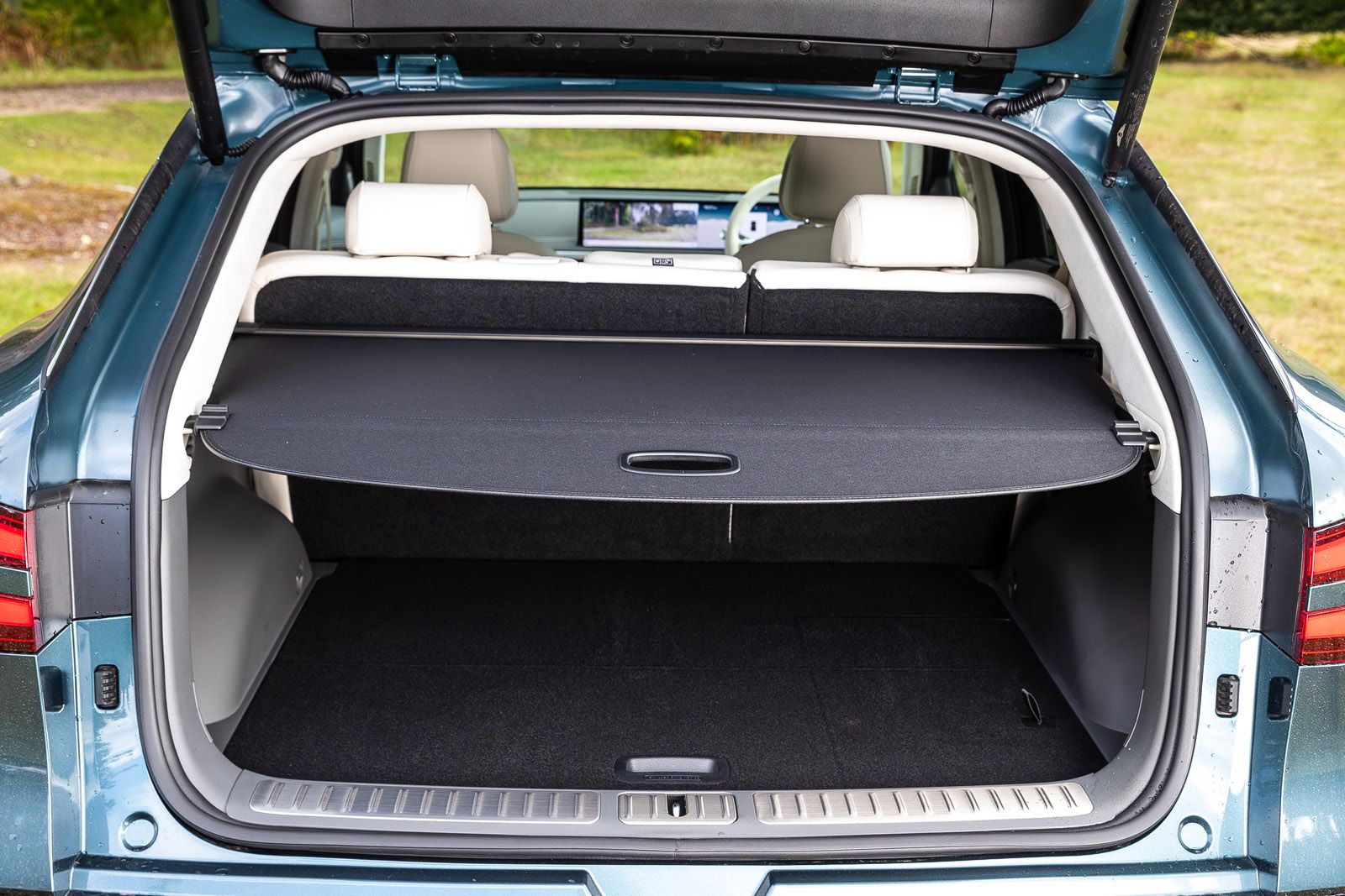 Open trunk of a blue SUV with seats folded, displaying a spacious cargo area covered by a retractable cover. Interior details are visible.