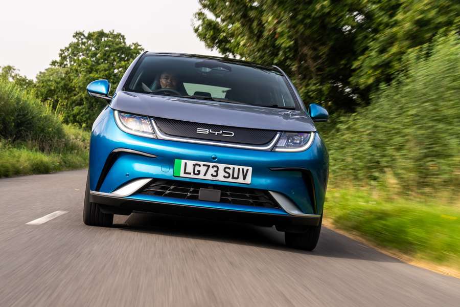 a blue byd dolphin driving on a country road