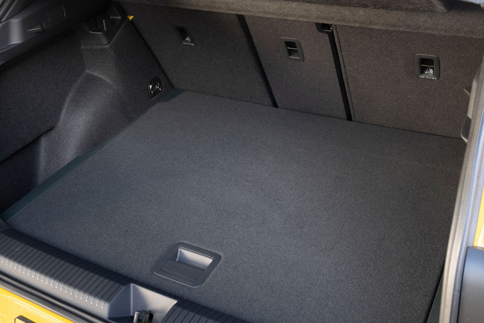 Open car trunk with a spacious, clean, carpeted interior and visible latches on the back seats.